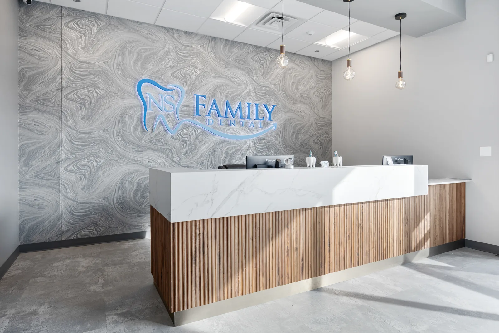 The reception area at NS Family Dental, with the practice logo on the feature wall